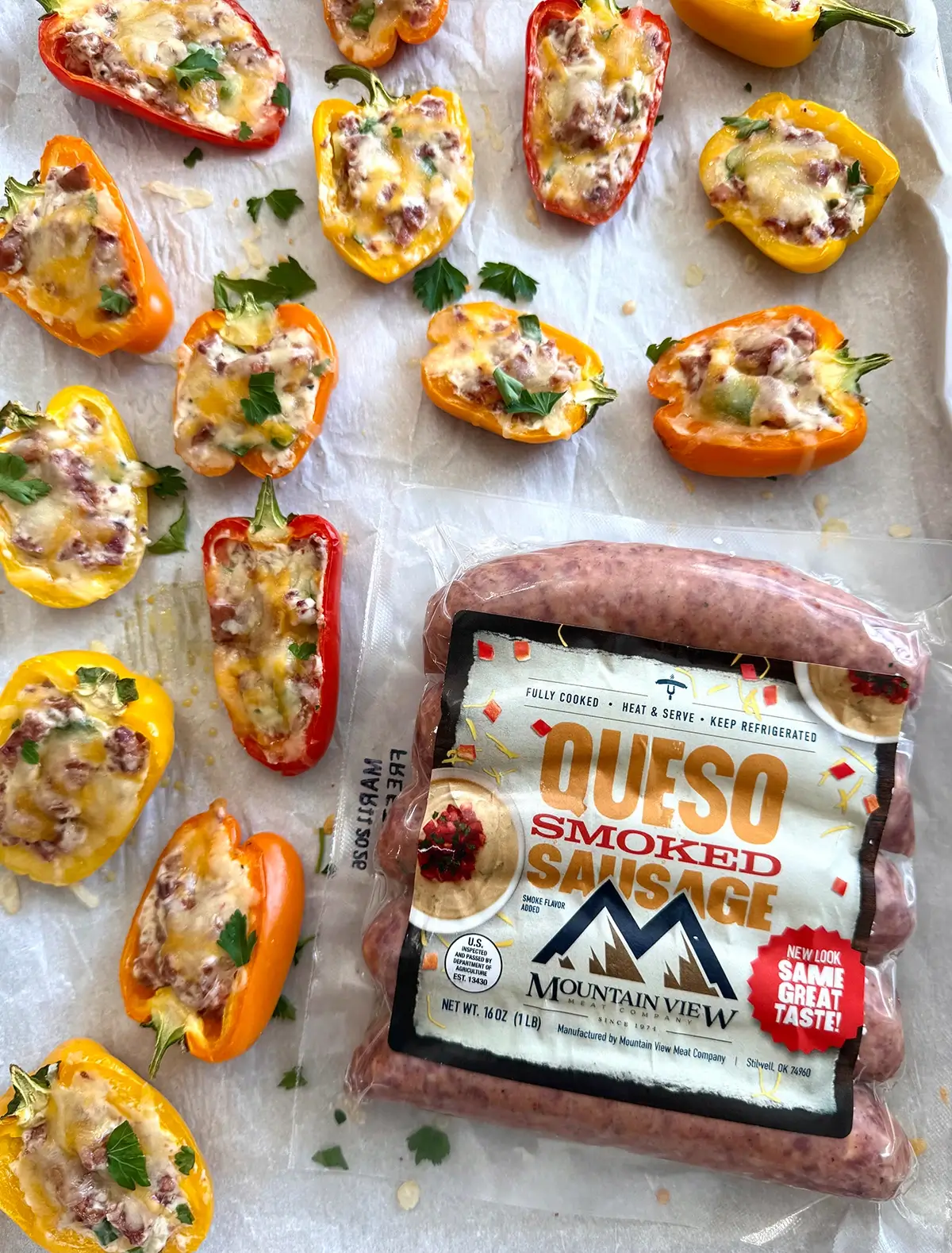Mini sausage stuffed peppers on a sheet pan next to a package of Mountain View Queso sausages