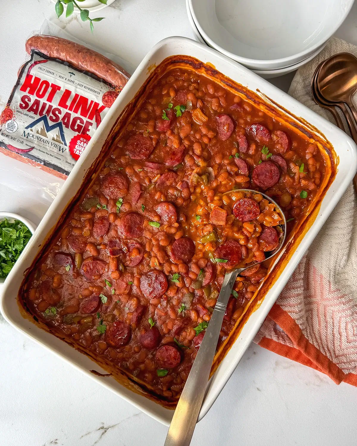 A pan of baked beans using Mountain View hot links with a ladle